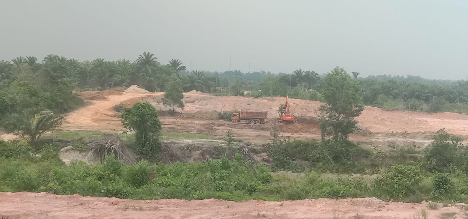 Foto alat berat sedang beroperasi memuat tanah timbun ke mobil dump truck di Kecamatan Dumai selatan